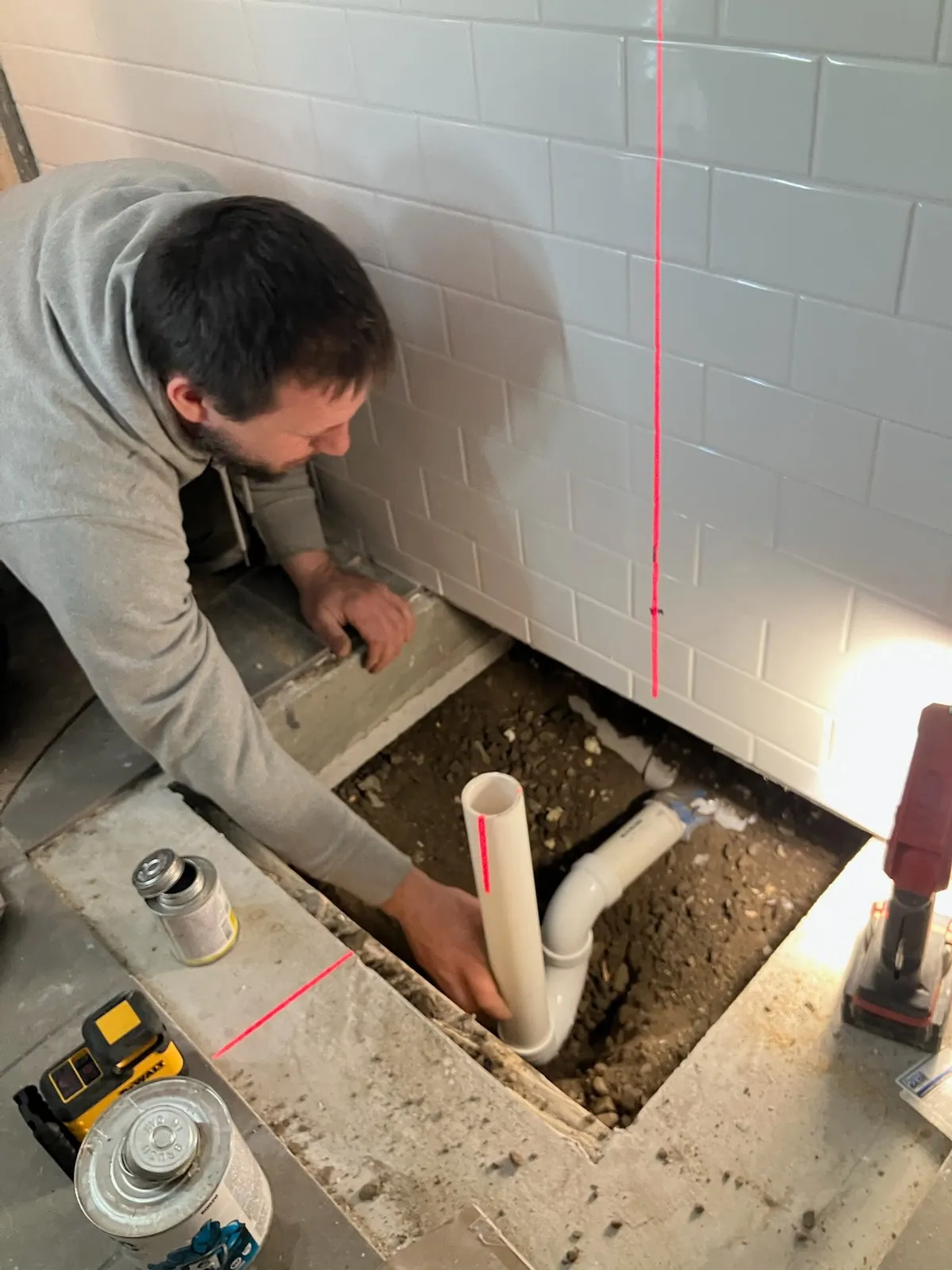 EZ-CO plumber setting a PVC shower drain and trap in a trench cut through a basement slab for a new bathroom