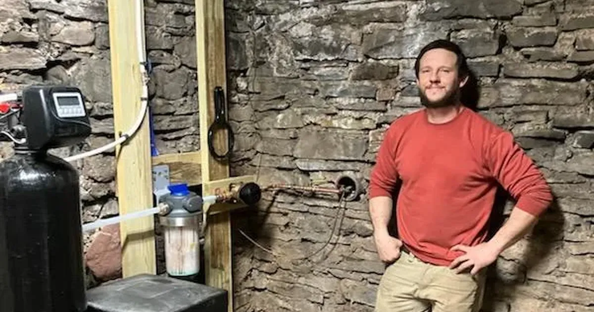 EZ-CO plumber beside a water softener and whole house sediment filter in a fieldstone basement in central New York