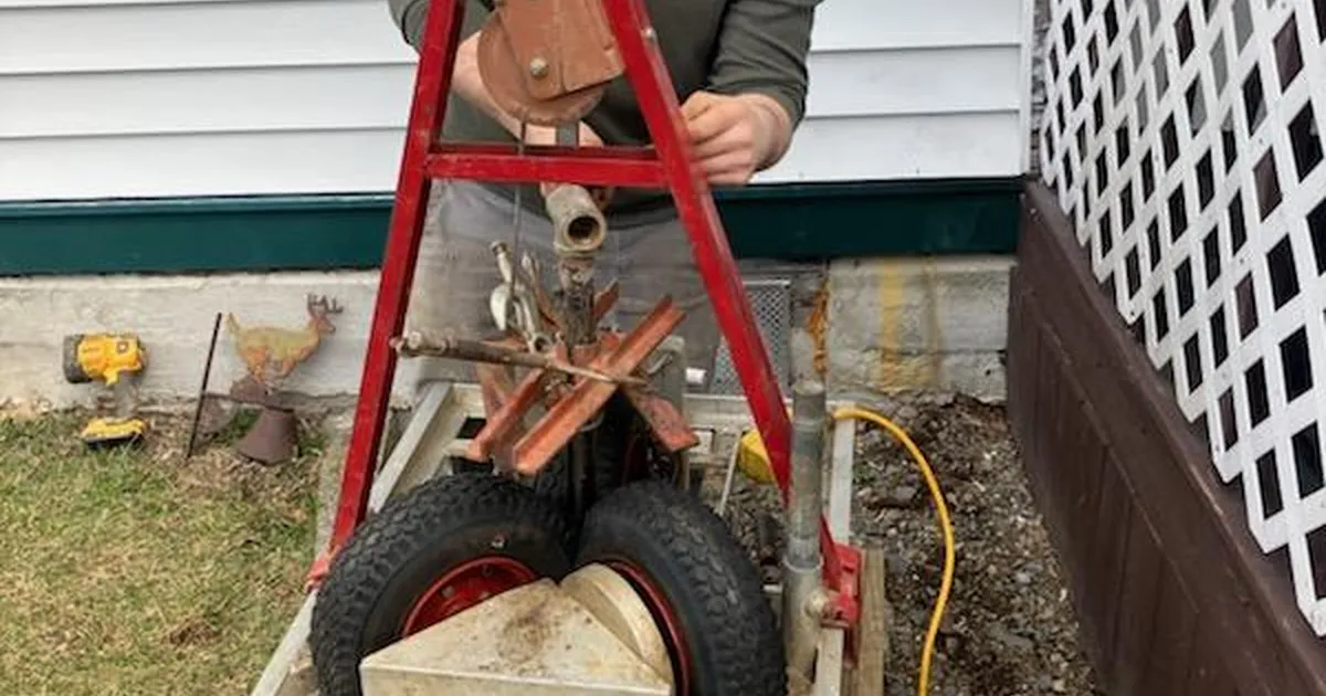 EZ-CO Plumbing sectional drain cleaning machine set up outside a home to clear a clogged main sewer line